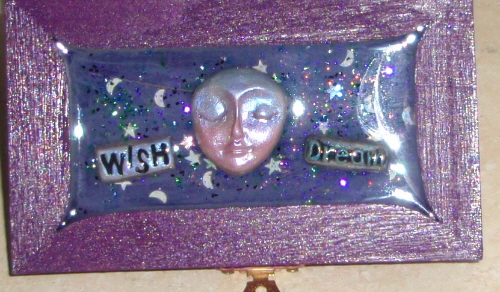 wish box top showing polymer clay pieces of moon face, wish word and sparkle stars in clear resin